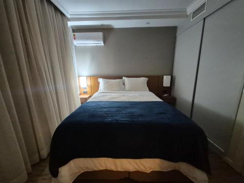 a bedroom with a large bed with a blue blanket at Flat Hotel Executivo Vila Olímpia (Apto 2509) in São Paulo