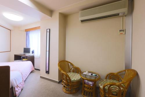 a bedroom with a bed and wicker chairs at Hotel Sunplaza Tsugaike in Otari