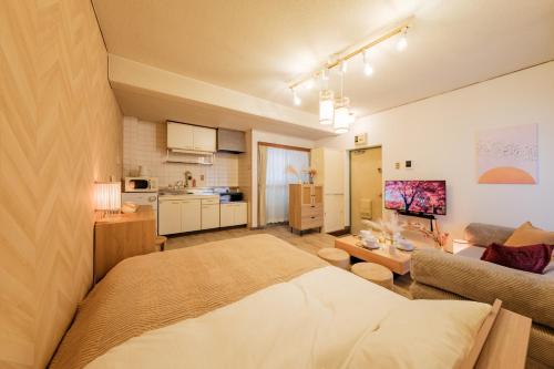 a room with a bed and a couch and a kitchen at Villa Fuchu Stay in Fuchu