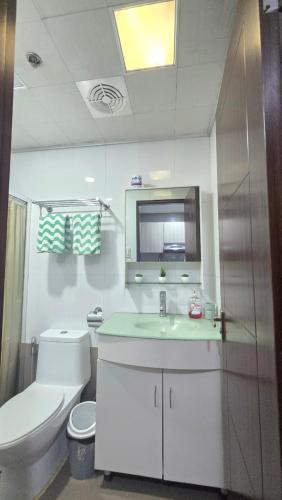 a bathroom with a toilet and a sink and a mirror at The Highland Condotel in Baguio