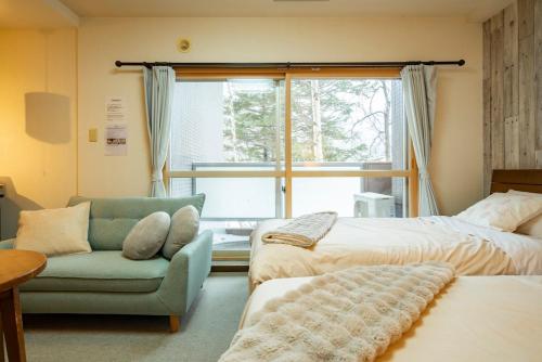 a bedroom with two beds and a chair and a window at Fewdays Condominium108 in Sapporo
