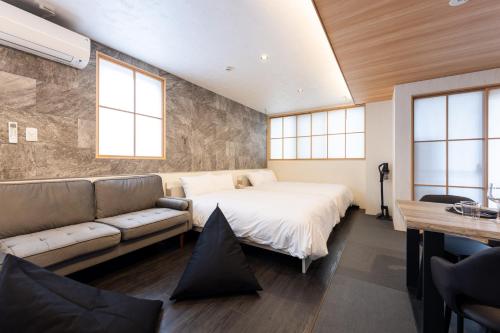 a bedroom with a bed and a couch and windows at WeskiiHotel in Kanazawa
