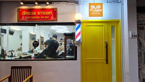 a yellow door of a store with a man in the window at SUP Hometel Phuket in Ban Thalat Choeng Thale