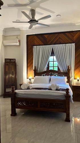 a bedroom with a large bed with a ceiling fan at Astana Az-Zahrah in Bahau