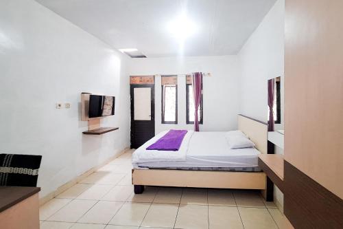 a bedroom with a bed and a tv in it at Villa Citra Syariah RedPartner in Kalibata 1