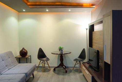 a living room with a couch and a tv and a table at Hotel Gilfer Puebla Centro Histórico in Puebla