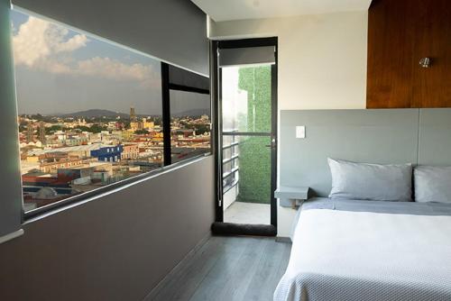 a bedroom with a white bed and a large window at Hotel Gilfer Puebla Centro Histórico in Puebla