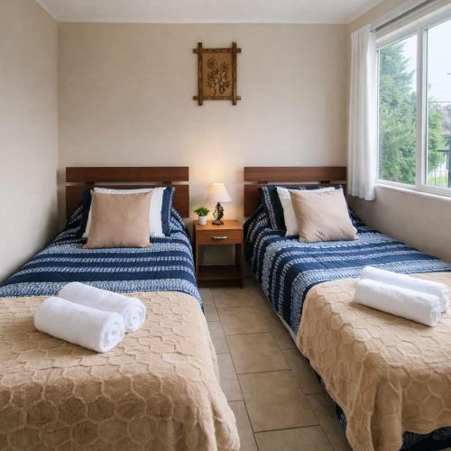 a bedroom with two beds and a window at Acogedora casa Pucón 6 personas, terraza, bosca, estacionamiento in Pucón