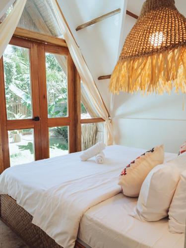 a bedroom with a bed with a window and a chandelier at Vibes Villas Siargao in General Luna