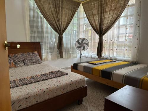 a bedroom with two beds and a window with curtains at Casa Campestre Kostal Azul in Tocaima