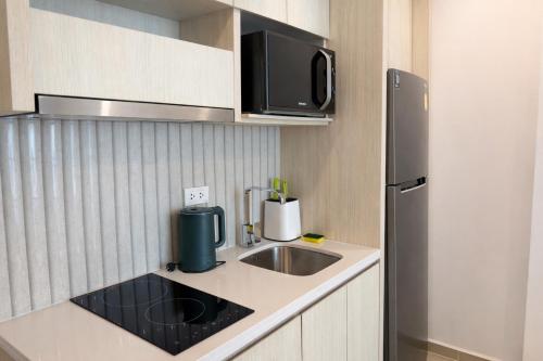 a small kitchen with a sink and a refrigerator at City Garden Lagoon Pool Apartments with Balcony Pattaya in Pattaya South