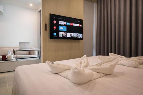 a bed with white towels on it with a flat screen tv at City Garden Lagoon Pool Apartments with Balcony Pattaya in Pattaya South