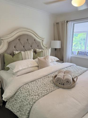 a white bed with a basket of towels on it at Firefly Cottage in Mount Tamborine