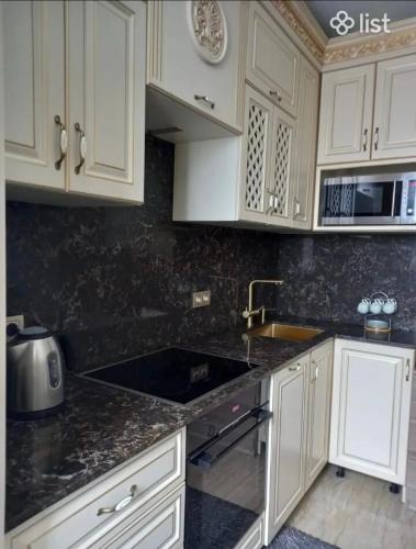 una cucina con mobili bianchi e un piano di lavoro nero di Avan House a Yerevan