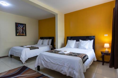 two beds in a room with yellow walls at Back Packer in Ibarra