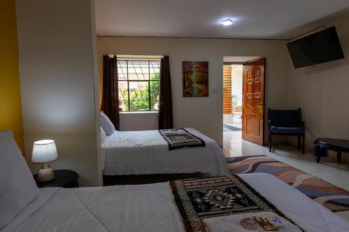 une chambre d'hôtel avec deux lits et une télévision dans l'établissement Back Packer, à Ibarra