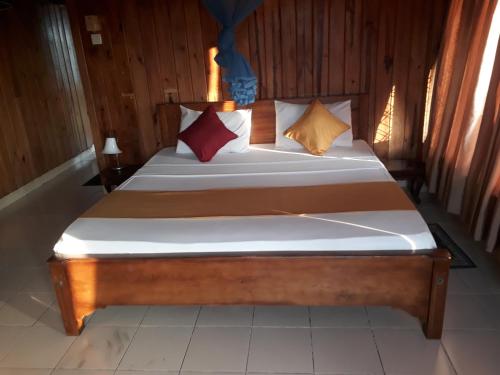 a bed with several pillows on it in a room at Wood cabin in Kandy