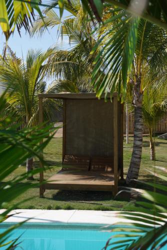 a bench next to a swimming pool with palm trees at Buena Vista in El Paredón Buena Vista