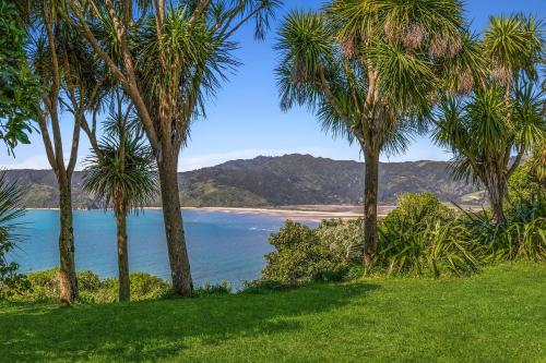 a view of a beach through palm trees at The Gatehouse - Tata Headlands in Tata Beach