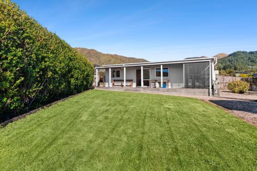 a house with a green lawn in front of it at Penguin Cottage in Tarakohe