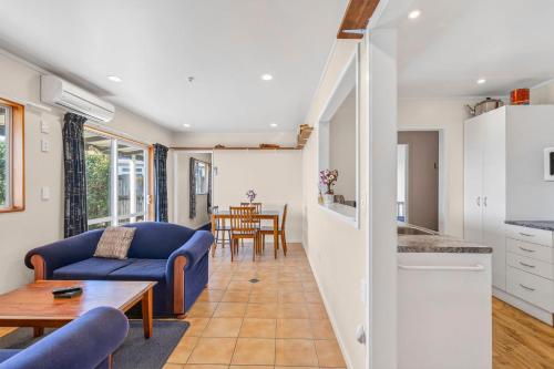 a living room with a blue couch and a table at Penguin Cottage in Tarakohe