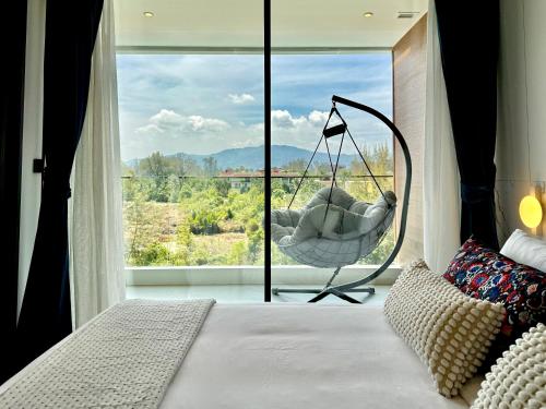 a bedroom with a swing in front of a large window at Sunshine by Villacarte in Layan Beach