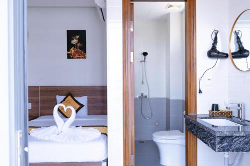 a bathroom with a swan on a bed and a bathroom with a sink at Sonne Hotel Quang Binh in Dong Hoi