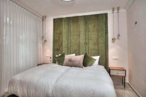 a bedroom with a large white bed with green walls at סוויטות סוויט - Suite in Safed