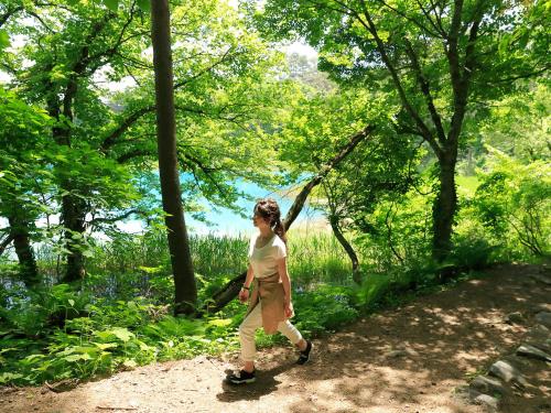 a woman walking on a path in the woods at Urabandai Lake Resort Goshiki no Mori in Kitashiobara