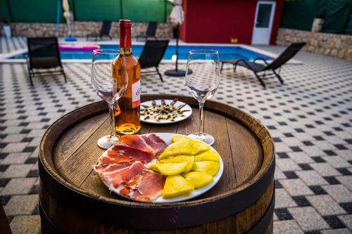 a table with a plate of food and two wine glasses at Villa Rubin with heated pool in Slivno