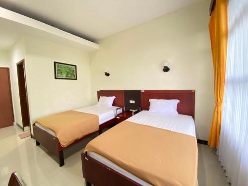 a hotel room with two beds and a window at Hortus Inn in Tawangmangu
