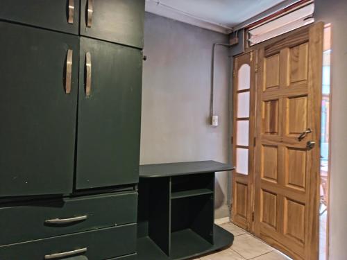 a kitchen with green cabinets and a desk next to a door at Casa Hostel Javi in Santiago