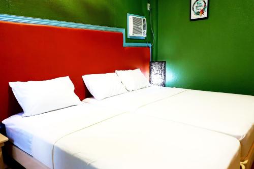 two beds in a room with a green and red wall at MJs Garden Hotel Moalboal powered by Cocotel in Moalboal