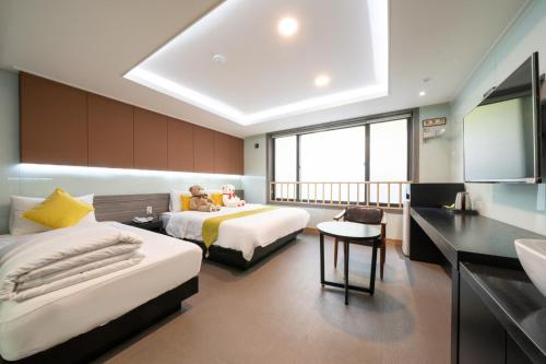a bedroom with two beds and a flat screen tv at Nampo MGM Hotel in Busan