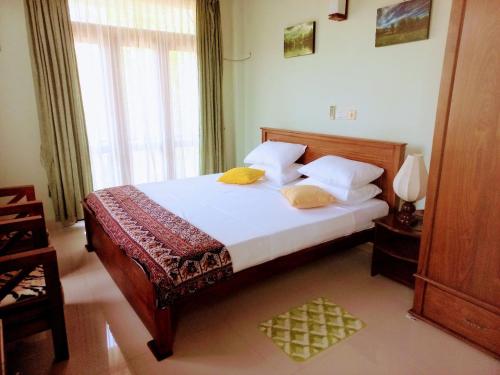 a bedroom with a bed with white sheets and yellow pillows at Villa 86 in Pamunugama