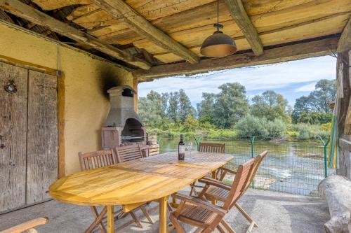 a wooden table and chairs on a patio with an outdoor oven at River View Suite Mlinar Private Beach - Happy Rentals in Metlika