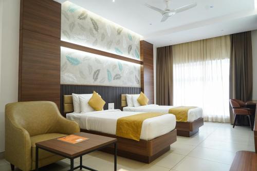a hotel room with two beds and a chair at Highland Hotel in Bangalore