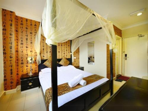 a bedroom with a canopy bed with white sheets at Seeds Hotel Shah Alam Seksyen 7 I-City in Shah Alam