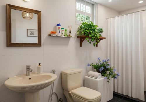 a white bathroom with a toilet and a sink at Tiny Art House with Garden in Godagama