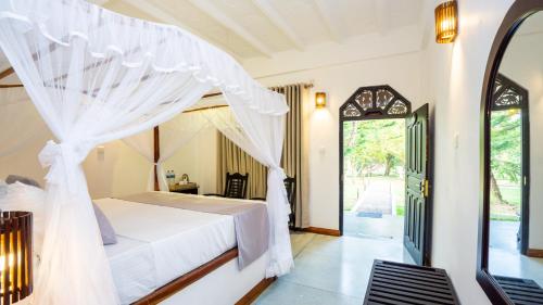 a bedroom with a bed with a mosquito net at La Roche Hotel Sigiriya in Sigiriya