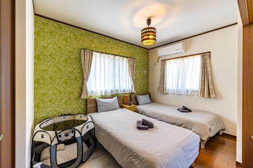 two beds in a room with green walls at Unbi Stay in Nakijin