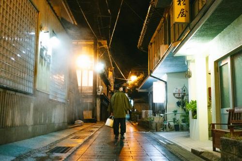 a man walking down a street at night at Tawarayama Machigoto Ryokan in Nagato