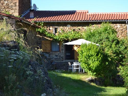 ein Haus mit einem Tisch und einem Sonnenschirm im Hof in der Unterkunft Holiday home with terrace in Villeneuve-dʼAllier