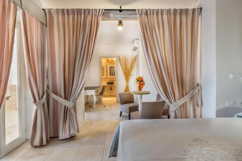 sypialnia z zasłonami, stołem i krzesłami w obiekcie Mannois - Lofts & Apartments w mieście Orosei