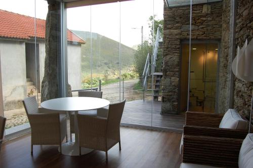 a table and chairs in a room with a large window at Quinta dos Castanheiros - Turismo Rural in Negreda