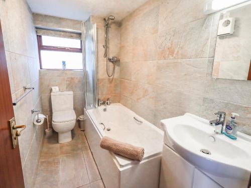 a bathroom with a sink and a toilet and a bath tub at Ghyll Bank Bungalow in Staveley