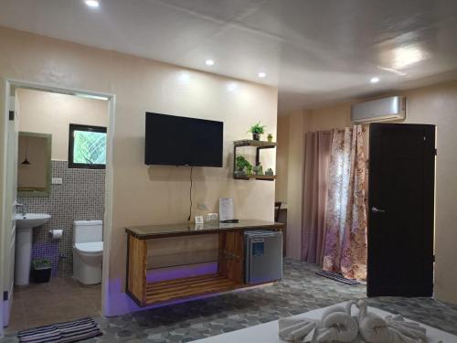 a bathroom with a toilet and a television on the wall at Datoni Italian Restaurant in Tabigue