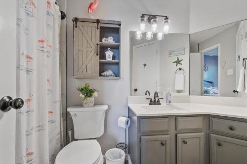 a bathroom with a toilet and a sink and a mirror at Island Palms - 2 min walk to the Beach in Corpus Christi
