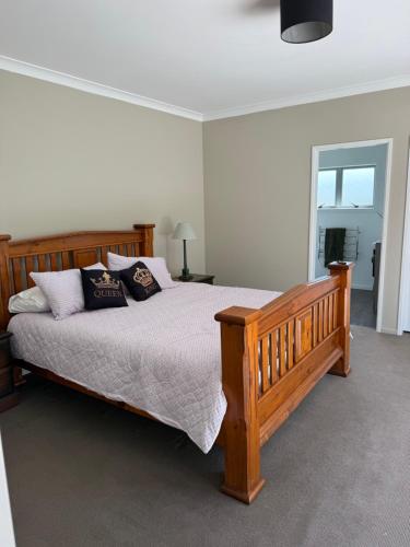 a bedroom with a large wooden bed with pillows at The King's Rest in Matamata