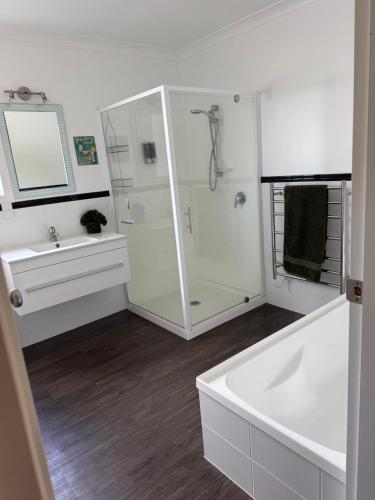 a bathroom with a shower and a tub and a sink at The King's Rest in Matamata